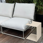 Cremeweißer Beistelltisch neben weißem Outdoor-Loungesofa auf Holzterrasse